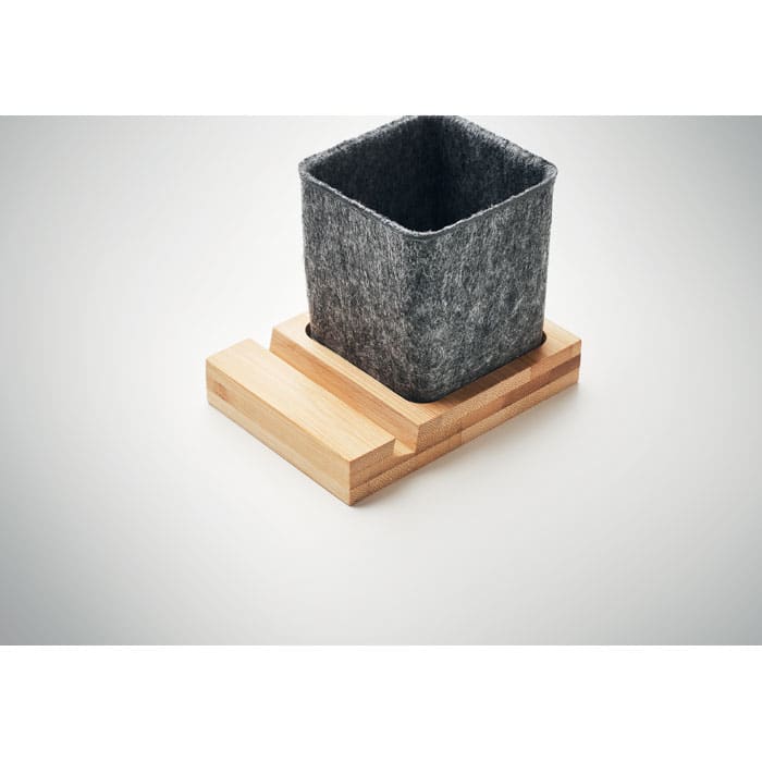 A grey felt planter cube sits on a light wooden base. The design is simple and modern.