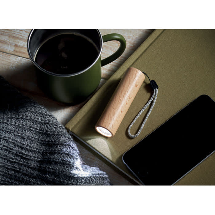 A drink bottle in natural wood finish beside a green mug and a smartphone on a textured surface.