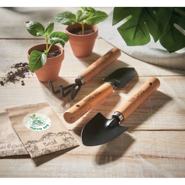 A set of gardening tools with wooden handles, including a trowel, a cultivator, and small pots with plants.