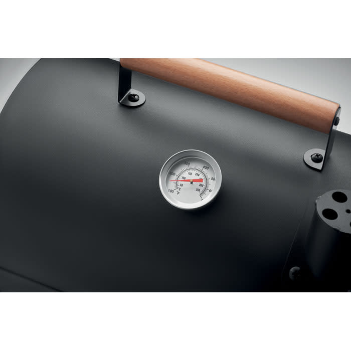 A black grill with a wooden handle and a round metal temperature gauge prominently displayed.