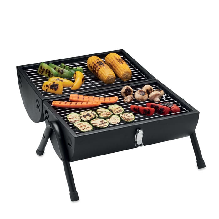 A portable black grill with grilled vegetables, including capsicum, corn, carrots, zucchini, and mushrooms on the rack.