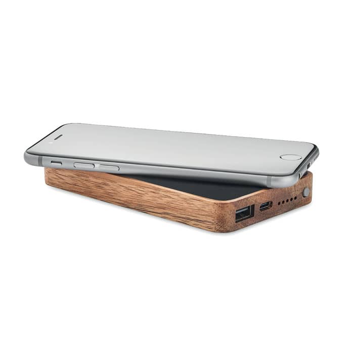 A power bank with a wooden exterior, featuring USB ports and a sleek design, with a smartphone resting on top.