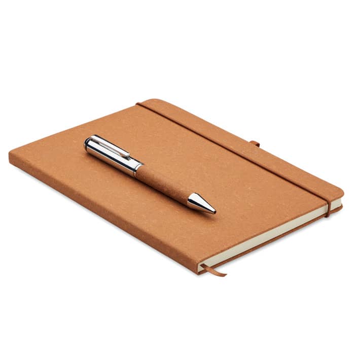 A tan notebook with a pencil tucked neatly on top, featuring a logo on the notebook cover.