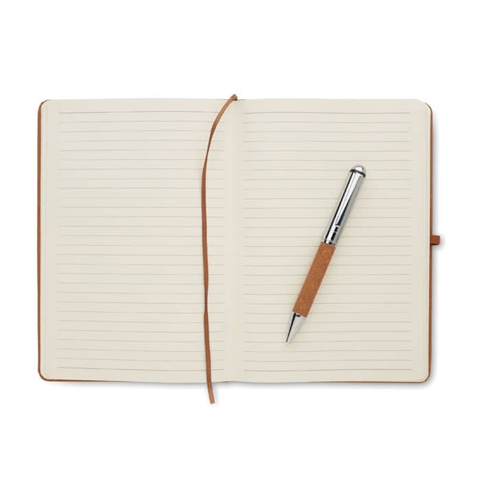 A brown notebook with lined pages and a silver pen resting on it. The notebook features a ribbon bookmark.