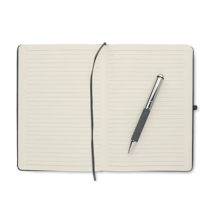A notebook with lined pages and a grey pen resting on it. The notebook features a black cover.