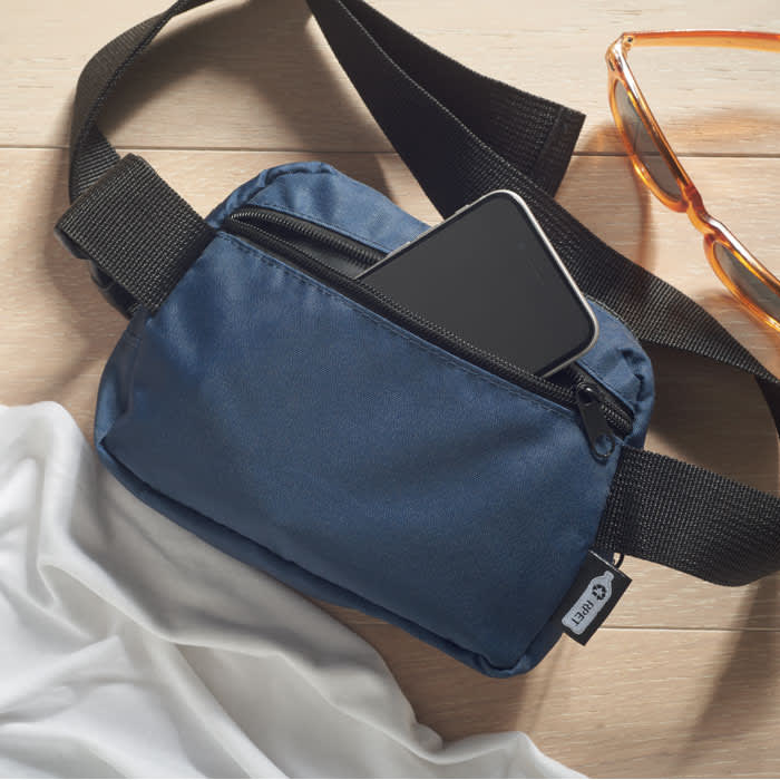 A navy blue shoulder bag with a zippered pocket, featuring an accessible smartphone inside and a black strap.