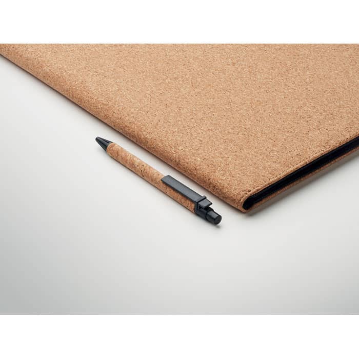 A cork notebook and a black pen on a light background, showcasing natural cork texture.