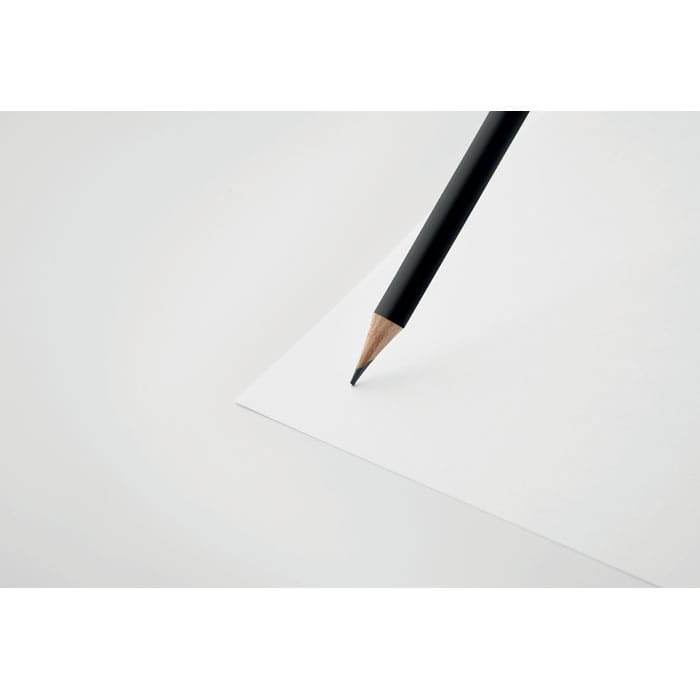 A black pencil poised above a blank white sheet of paper on a surface.