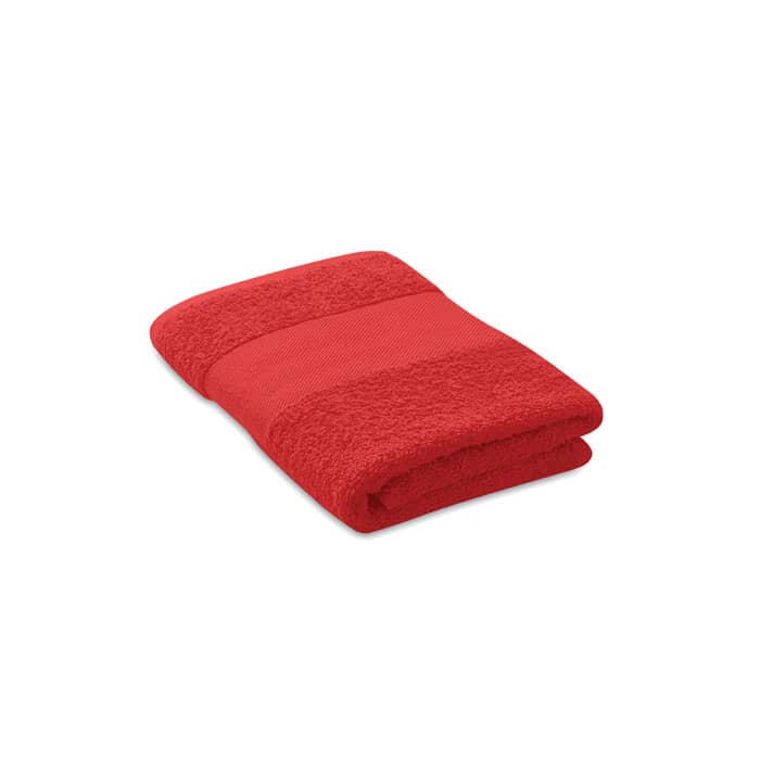 A red towel folded neatly with textured bands. The product features a simple design.