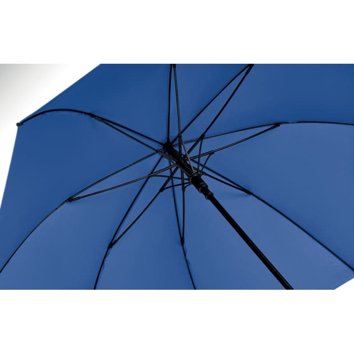 A blue umbrella viewed from underneath, showcasing its structure and ribs against a light background.