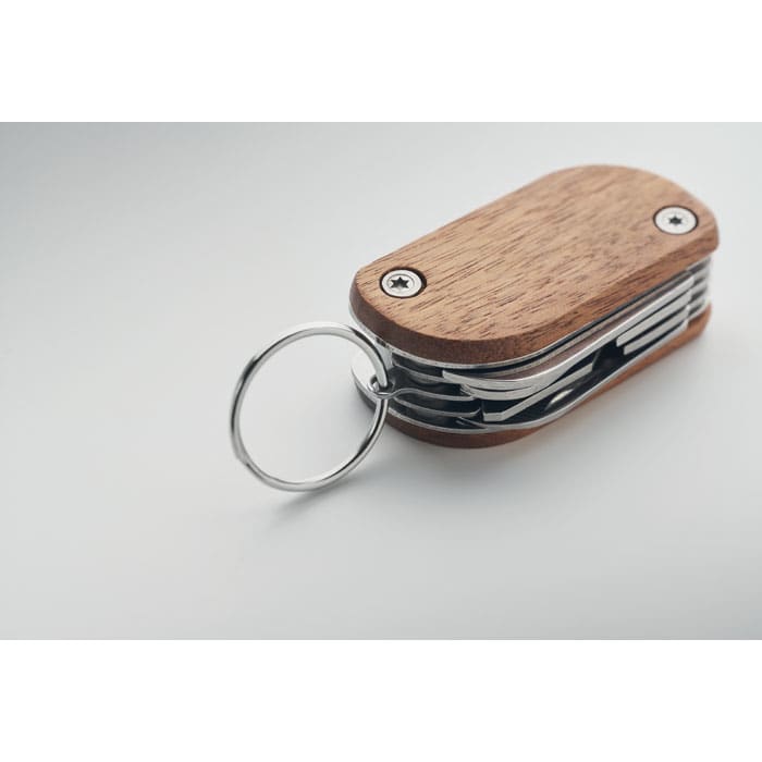 A multifunctional keychain tool with a wooden case and stainless steel implements, featuring a metal ring attachment.
