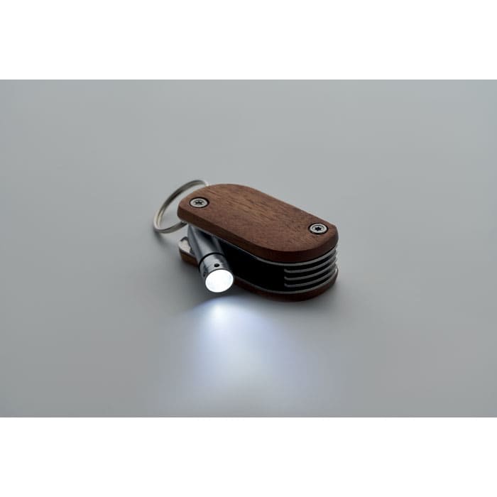 A wooden and metal keychain with a small flashlight, featuring a sleek design and a keyring attachment.