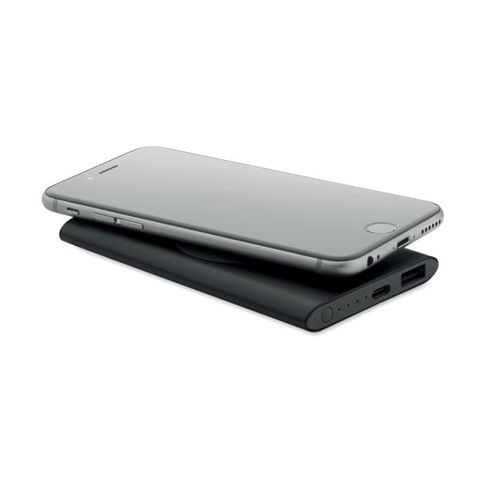 A sleek black power bank with a smartphone resting on top, featuring various connectivity ports.