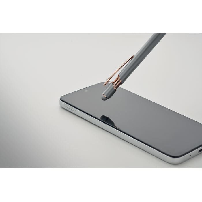 A grey pen with a rose gold clip poised above a sleek black smartphone on a light-background surface.