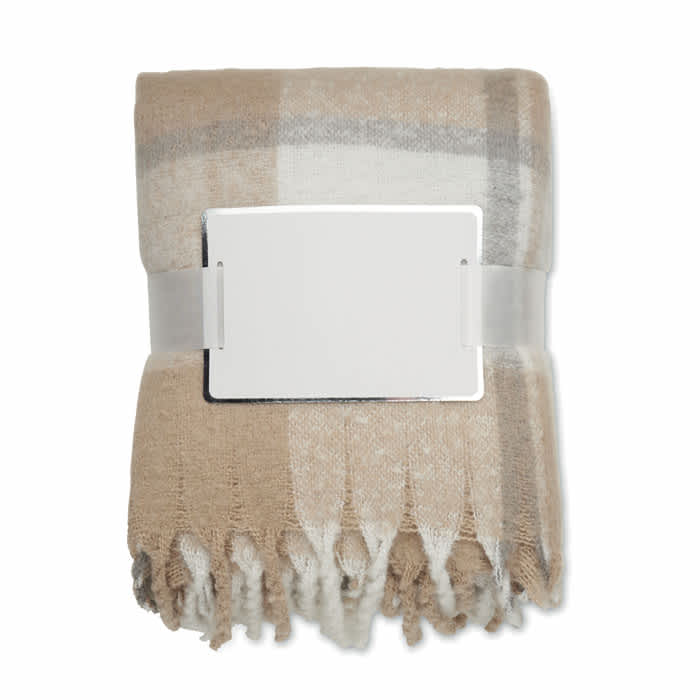 A folded blanket in shades of beige and grey, secured with a silver buckle. The blanket features a checkered pattern and fringe edges.