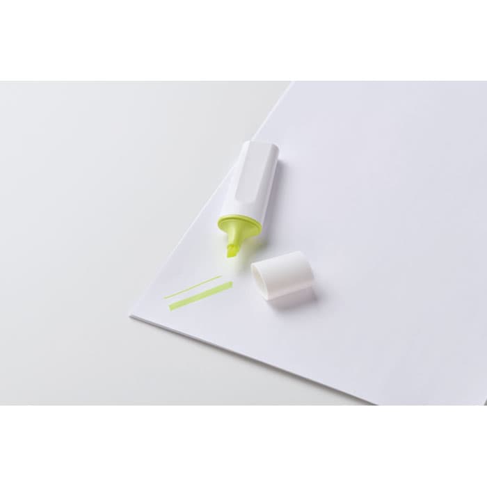 A highlighter pen in bright yellow with a white casing, placed on a sheet of white paper.