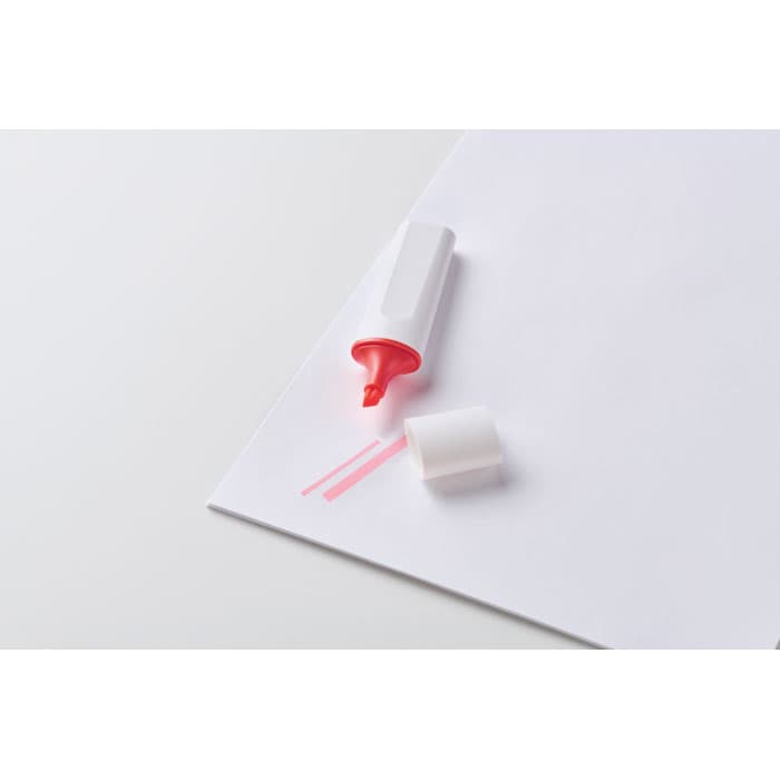 A pink highlighter on a white sheet of paper, with its cap removed and placed beside it.