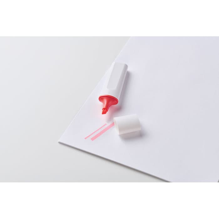A highlighter with a pink ink tip lies on a sheet of white paper, cap off. It features a simple design.