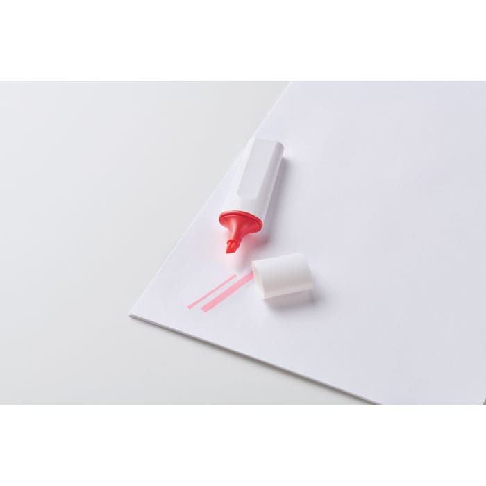 A pink highlighter with a white cap resting on a sheet of paper. The cap is off, revealing the bright tip.