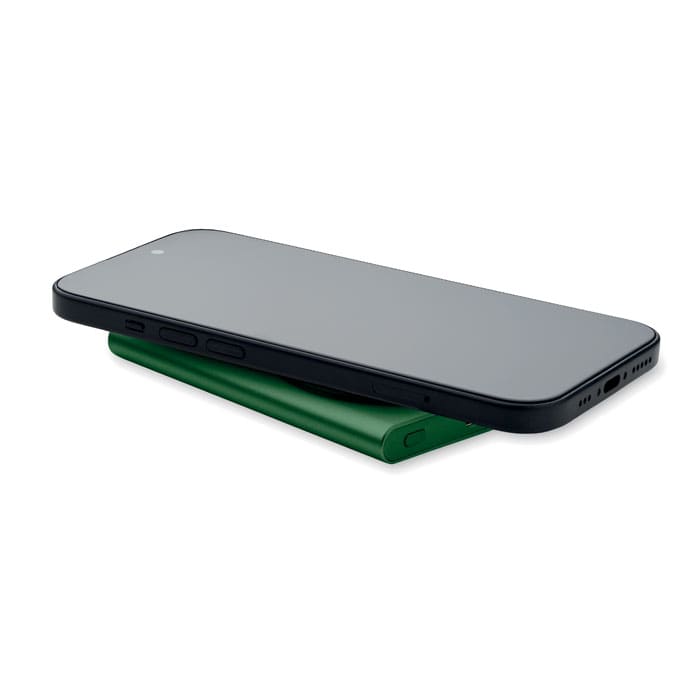 A green charging bank is placed under a black smartphone. The setup features a sleek design with a minimalist look.