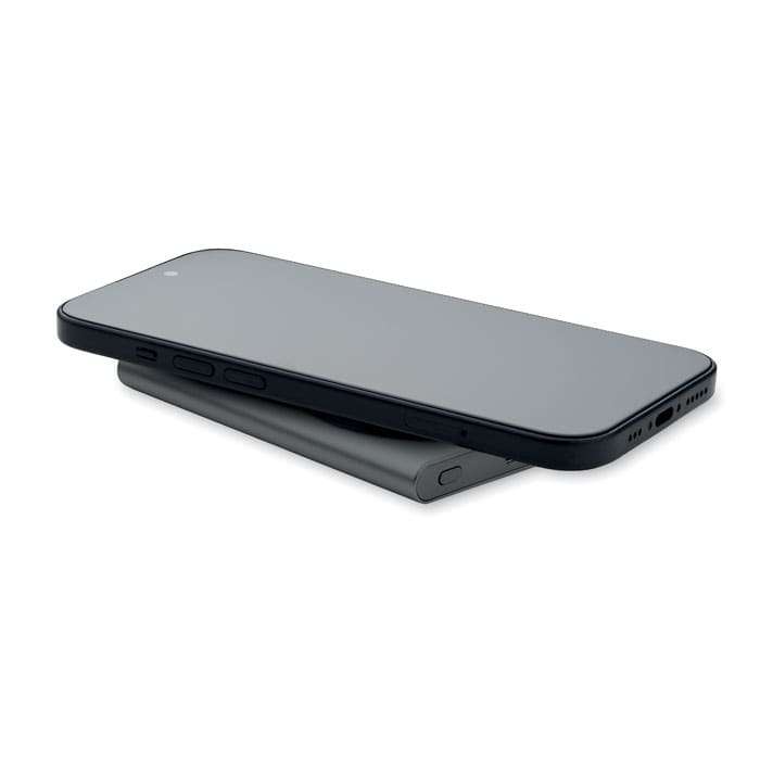 A sleek black smartphone rests on a grey charging pad, featuring a minimalist design with no visible logos.
