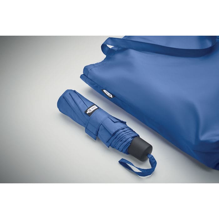A blue umbrella folded beside a matching blue tote bag, both featuring a logo.