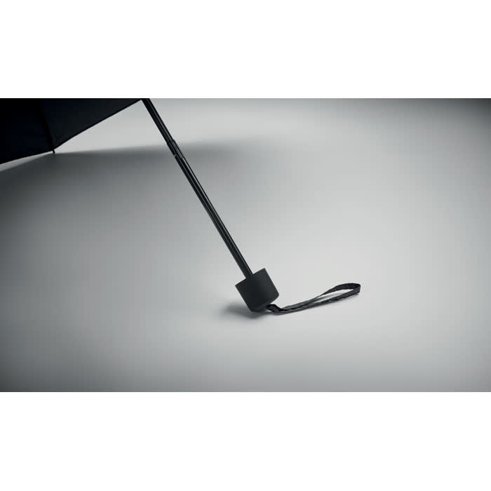 A black umbrella with a sleek handle and strap, resting on a simple background. It features a minimalist design.