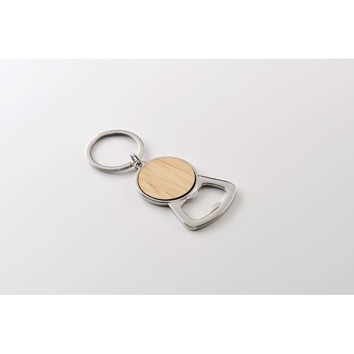 A keyring bottle opener featuring a wooden circular section and a metallic bottle cap remover.