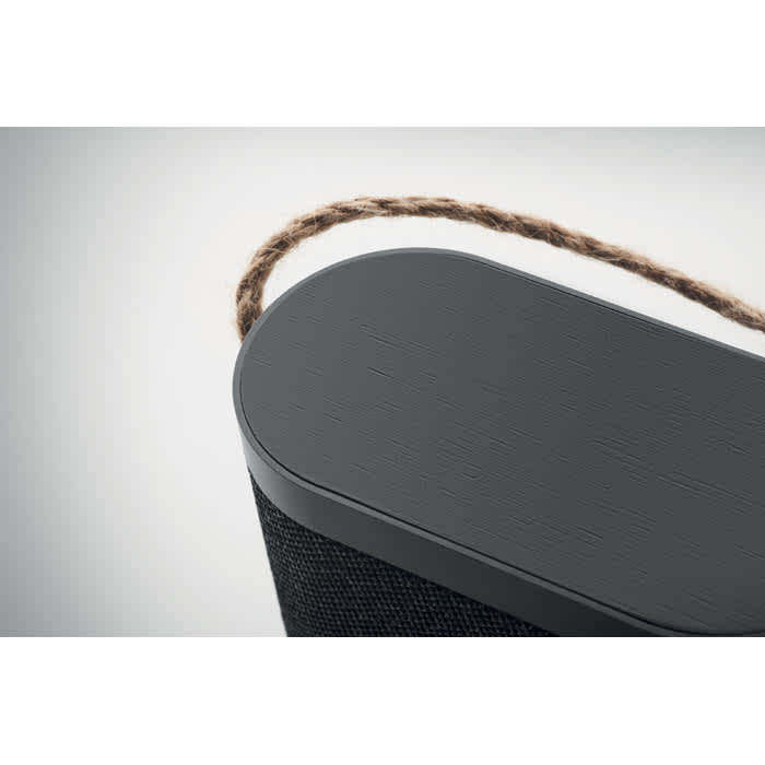A black portable speaker with a textured surface and a woven carry handle on the top.