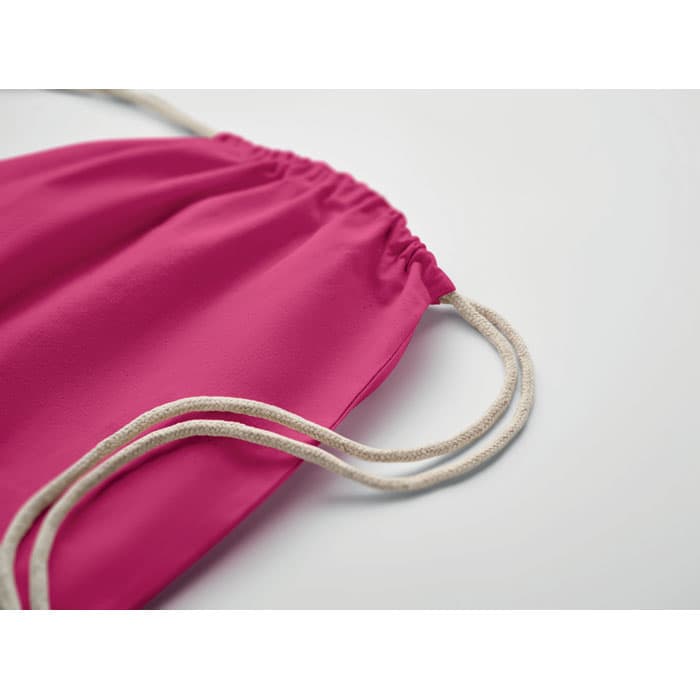 A drawstring bag in vibrant pink with beige cords for closure. It features a simple, modern design.