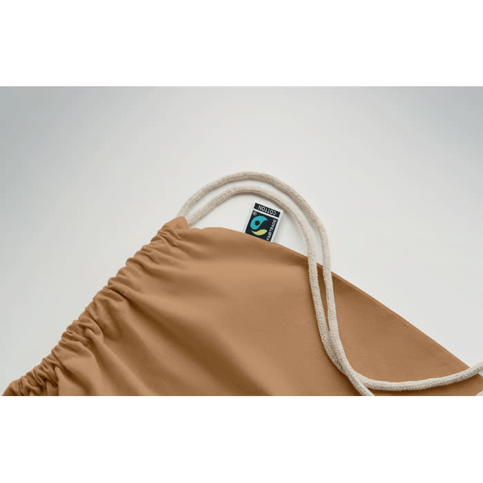 A tan drawstring bag with a white cord and a small logo visible on the interior seam.