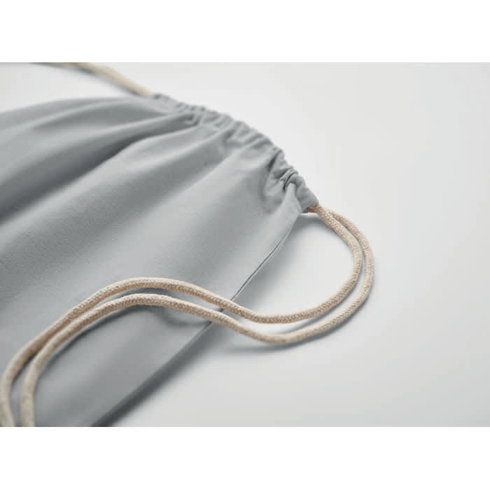 A grey drawstring bag with beige cords, featuring gathered fabric at the opening and a simple design.