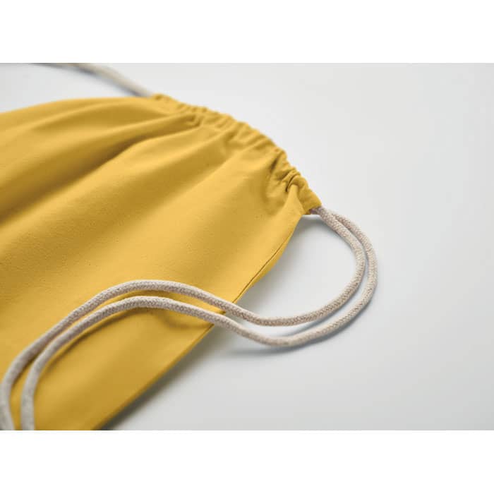 A drawstring bag in a vibrant yellow colour with light-coloured cords. The bag features a gathered opening.