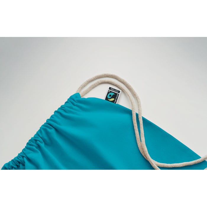 A drawstring bag in vibrant turquoise, featuring a branded tag and natural-coloured cord.