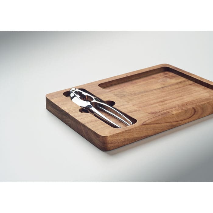 A wooden serving board with a sleek design, featuring a metal nutcracker included in a cut-out section.