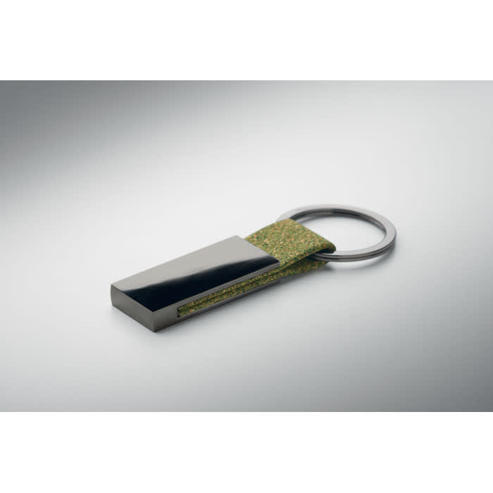 A keyring featuring a metallic grey rectangular piece with a green fabric strap.