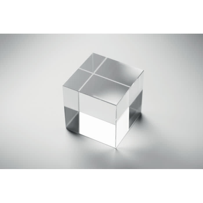 A clear, transparent cube with several flat surfaces reflecting light on a smooth grey background.