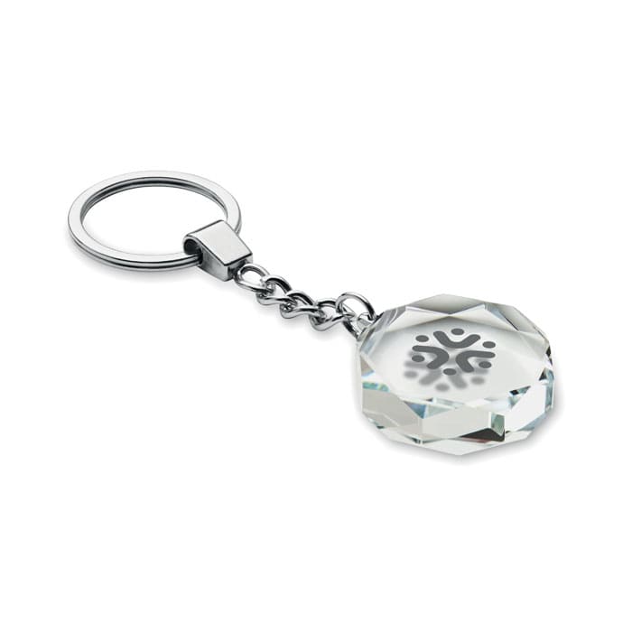 A clear crystal keychain with an octagonal shape and a metallic keyring attachment. It features a logo on one side.