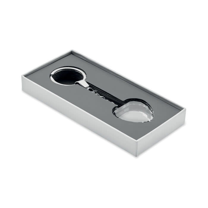 A boxed keychain featuring a round metal keyring and a heart-shaped attachment, presented on a black tray.