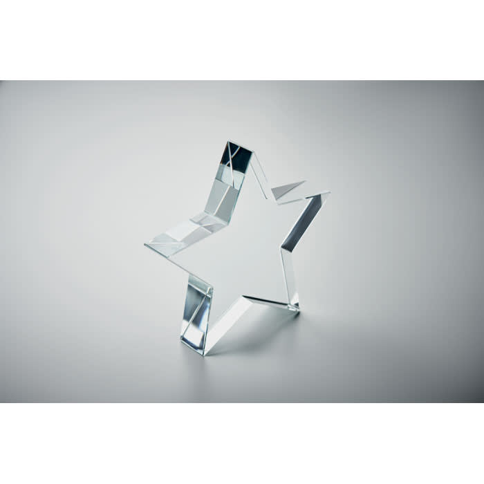 A clear star-shaped crystal figurine with sharp edges and a reflective surface.