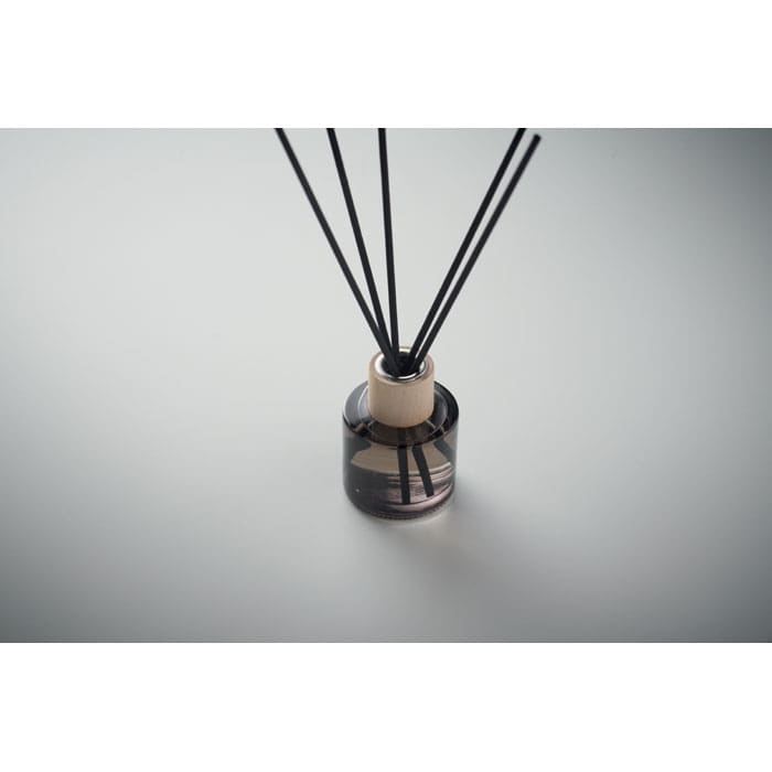A glass diffuser bottle in dark grey with black reeds. The design features a minimalist style and wooden accents.