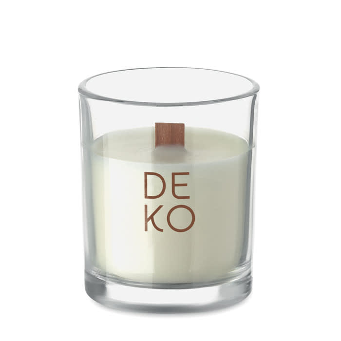 A glass candle with a wooden wick, filled with white wax, featuring a simple logo on the front.