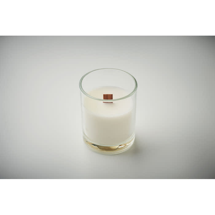 A candle in a clear glass holder with a wooden wick, featuring a white wax interior.
