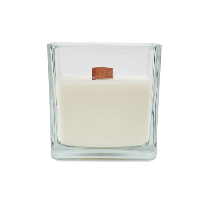 A square glass candle holder contains a creamy white candle with a wooden wick in the centre.