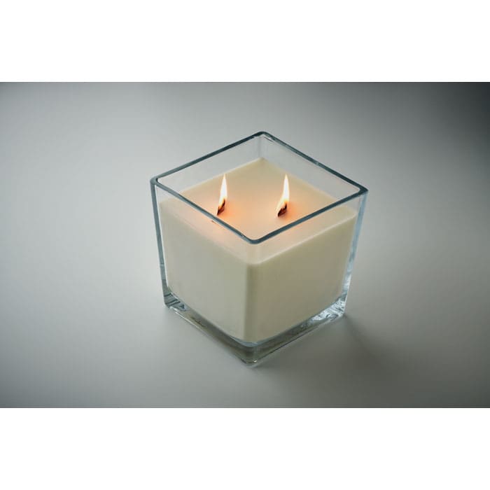A candle in a square glass holder with two flames, featuring a creamy white wax.
