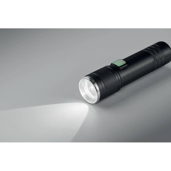 A torch with a sleek black design shines a bright beam of light, featuring a textured grip and a side button.
