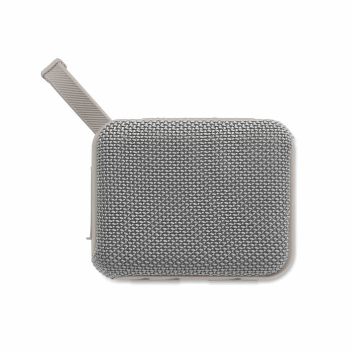 A portable speaker with a textured grey fabric cover and a side handle. It features a minimalist design and has a logo.