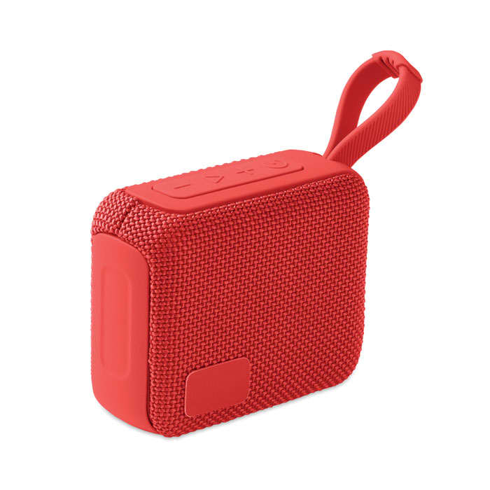 A portable speaker in bright red with a textured fabric surface and a loop for easy carrying.