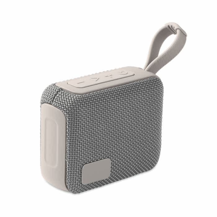A grey portable speaker with a textured fabric exterior and a strap for easy carrying. It features control buttons on the top.