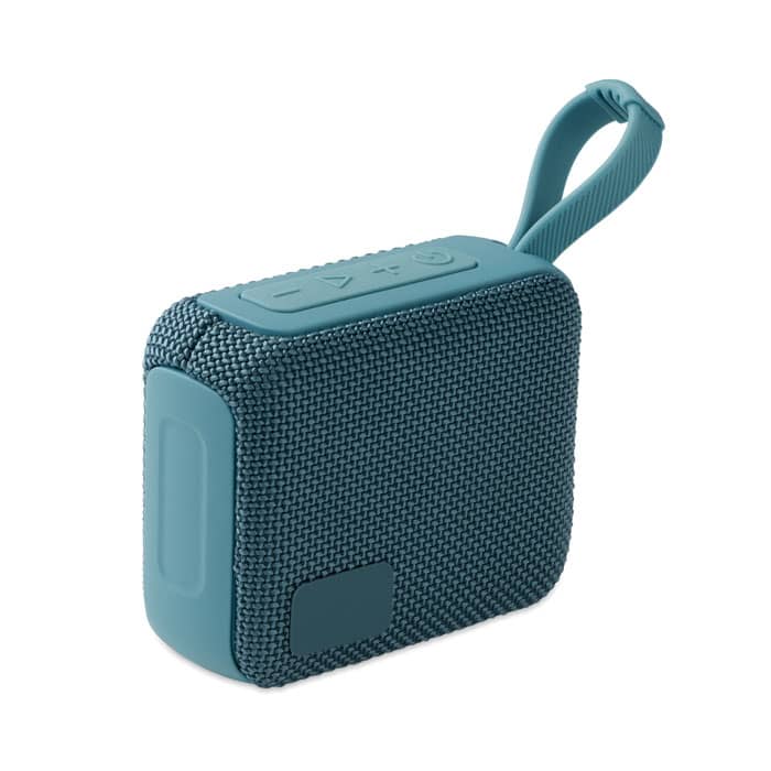 A portable speaker in teal with a textured finish and a carry strap, featuring control buttons on top.